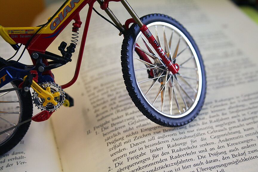 Deutscher Gesetzestext mit Fahrradbezug Miniatur-Fahrrad steht auf einem aufgeschlagenen Buch mit deutschem Gesetzestext.